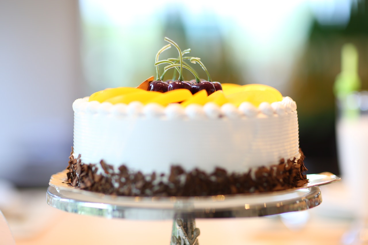 White round cake topped with yellow sliced fruit