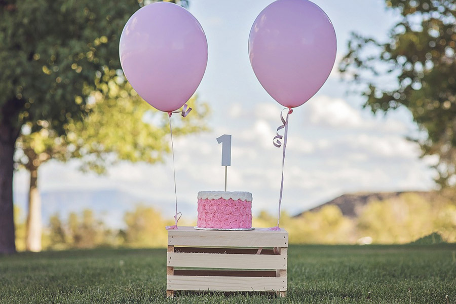 pink sweets on top of a table with two balloons